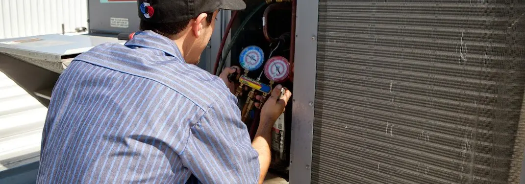 HVAC technician servicing a condenser unit in Warrington