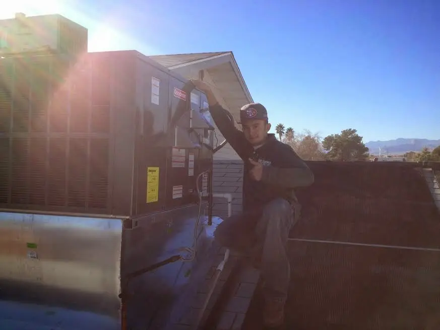 HVAC technician performing AC Tune-Up on a rooftop unit in Warrington